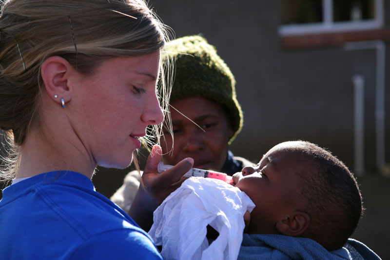 Peace Corp volunteer feeding an infant